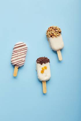 Mousse dessert with fruit flavors in the form of popsicle ice cream on blue background. Mousse dessert with fruit flavors in the form of popsicle ice cream covered with white chocolate on blue background. Copyright: xZoonar.com BurakovaxIrinax 18231170