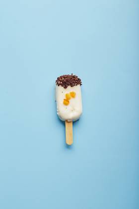 Mousse dessert with fruit flavors in the form of popsicle ice cream on blue background. Mousse dessert with fruit flavors in the form of popsicle ice cream covered with white chocolate on blue background. Copyright: xZoonar.com BurakovaxIrinax 18286077