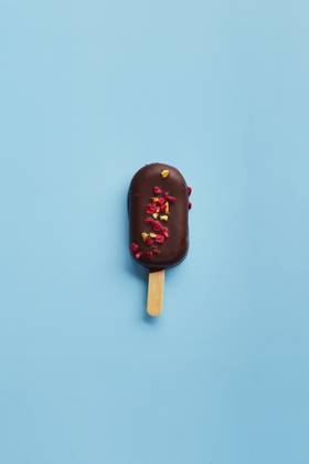Mousse dessert with fruit flavors in the form of popsicle ice cream on blue background. Mousse dessert with fruit flavors in the form of popsicle ice cream covered with dark chocolate on blue background. Copyright: xZoonar.com BurakovaxIrinax 18286248