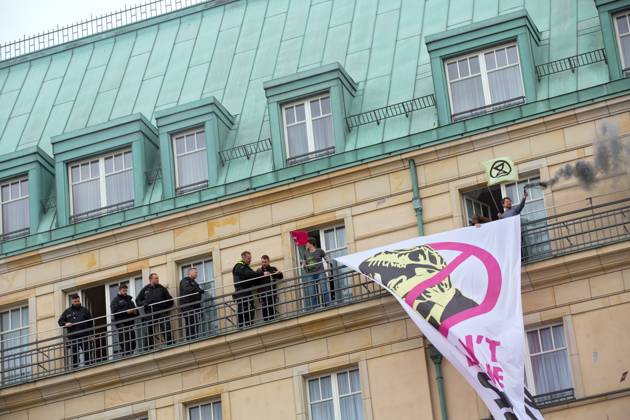 Berlin, Germany, DEU Extinction Rebellion, climate activists hijack Hotel Adlon 13.04.23, Berlin, Germany, DEU Extinction Rebellion, climate activists hijack Hotel Adlon Protesters add smoke candles and unfurl a banner on the balcony of one of the upper floors that reads We can™t afford the super rich Police officer