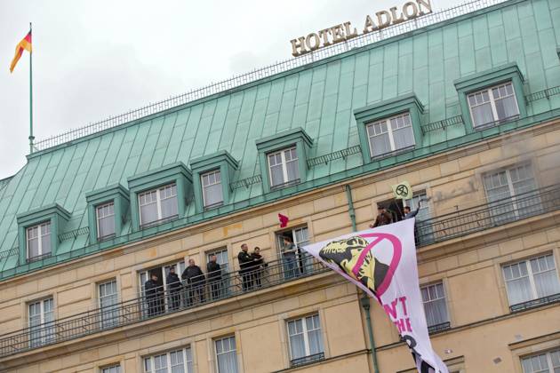 Berlin, Germany, DEU Extinction Rebellion, climate activists hijack Hotel Adlon 13.04.23, Berlin, Germany, DEU Extinction Rebellion, climate activists hijack Hotel Adlon Protesters add smoke candles and unfurl a banner on the balcony of one of the upper floors that reads We can™t afford the super rich Police officer