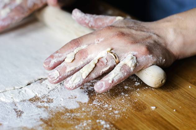 female hands using a rolling pin to pave a dough over a wooden board dirty with flour. female hands using a rolling pin to pave a dough over a wooden board dirty with flour. Preparation of flour-based food such as bread or pizza Copyright: xZoonar.com ValerioxRosatix 15245707