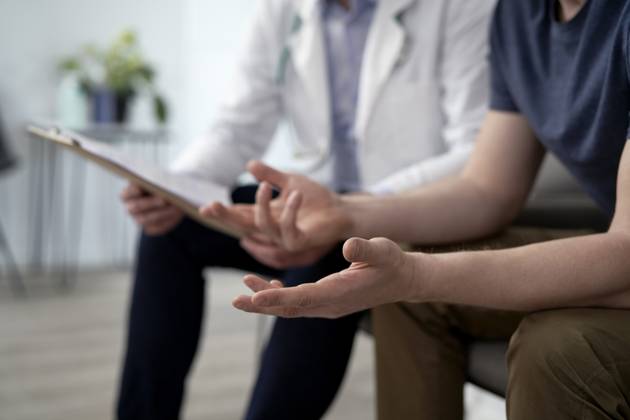 Man gesturing and discussing with doctor at clinic model released, Symbolfoto property released, ABIF01855