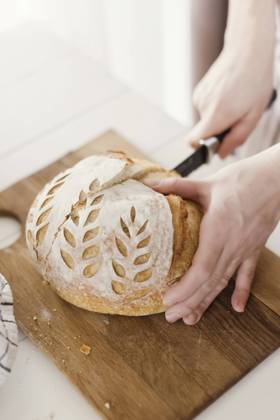 Hands of woman cutting loaf of bread on board model released, Symbolfoto property released, ONAF00486