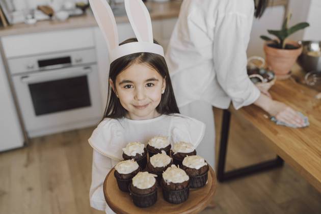 Smiling girl holding cupcakes on Easter day at home model released, Symbolfoto property released, VBUF00303