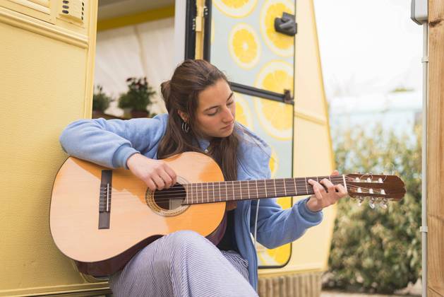 Young woman playing guitar at a campsite. Barcelona, Catalonia, Spain CR_RAFE230316-1148445-01 ,model released, Symbolfoto