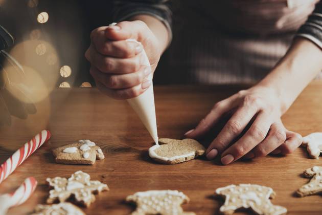Christmas, New Year food preparation. Gingerbread cookies decorating with icing Christmas, New Year food preparation. Xmas gingerbread cooking, making and decorating freshly baked cookies. Closeup on cropped shot with woman hands holding icing and mastic, decorating cookies Copyright: xZoonar.com OlenaxIvanovax 19091120