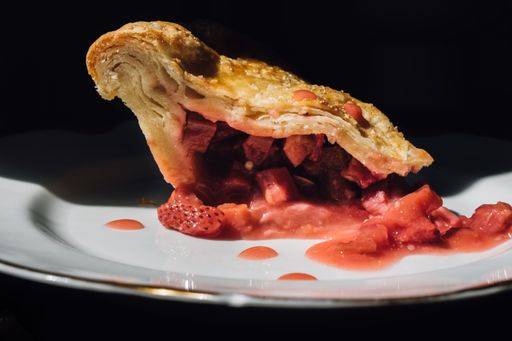 RECORD DATE NOT STATED A side view of strawberry rhubarb pie slice on white plate with black background *** einer Bordwand Ansicht des Erdbeere Rhabarber pie Scheibchen am weiß Teller mit Schwarz Hintergrund 4830656