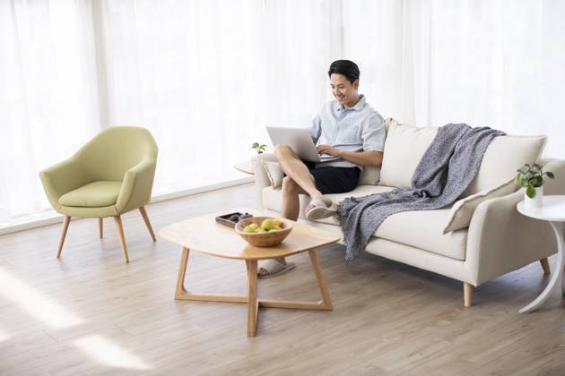 Happy young Chinese man using laptop in living room Beijing China Copyright: xLanexOateyx bji05860196