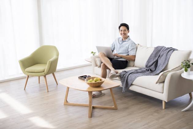 Happy young Chinese man using laptop in living room Beijing China Copyright: xLanexOateyx bji05860197
