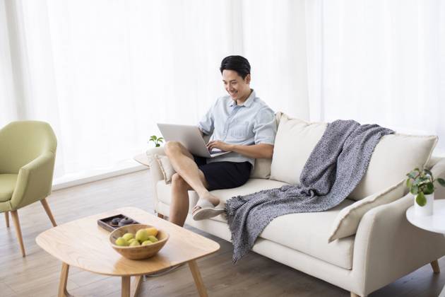 Happy young Chinese man using laptop in living room Beijing China Copyright: xLanexOateyx bji05860198