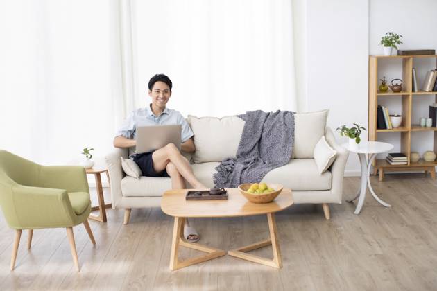 Happy young Chinese man using laptop in living room Beijing China Copyright: xLanexOateyx bji05860340