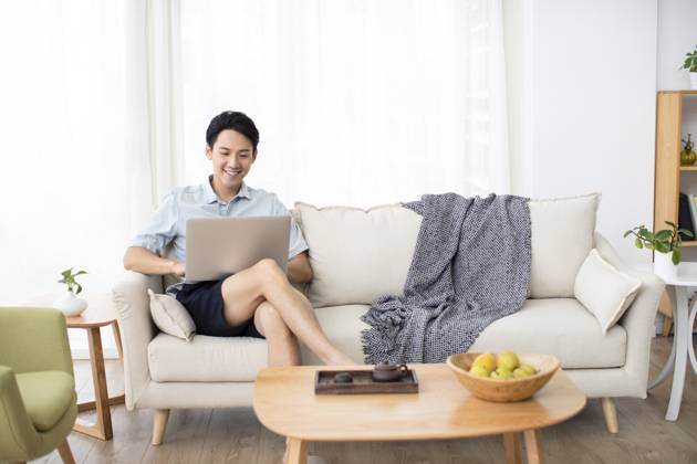 Happy young Chinese man using laptop in living room Beijing China Copyright: xLanexOateyx bji05860342