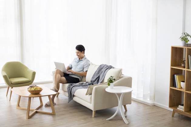 Happy young Chinese man using laptop in living room Beijing China Copyright: xLanexOateyx bji05860343