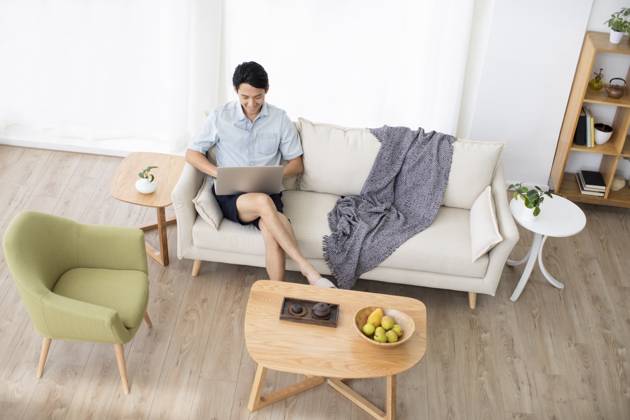 Happy young Chinese man using laptop in living room Beijing China Copyright: xLanexOateyx bji05860344