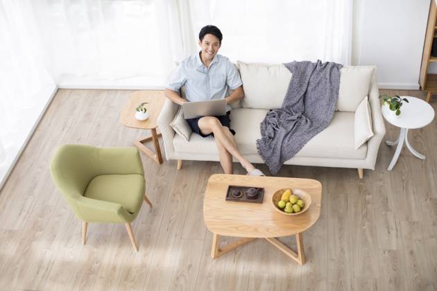 Happy young Chinese man using laptop in living room Beijing China Copyright: xLanexOateyx bji05860345