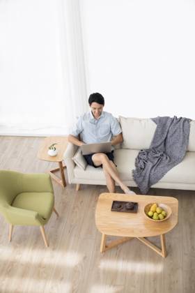 Happy young Chinese man using laptop in living room Beijing China Copyright: xLanexOateyx bji05860347