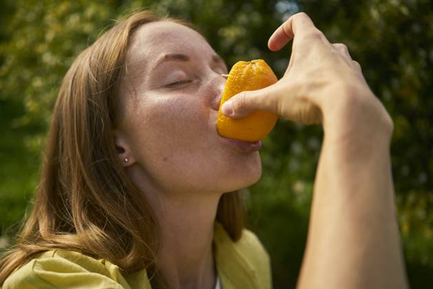 Woman with eyes closed eating fresh orange at orchard model released, Symbolfoto property released, ANNF00241
