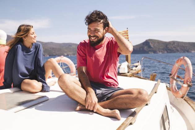Smiling man sitting cross-legged by woman on yacht at vacation model released, Symbolfoto, PCLF00478