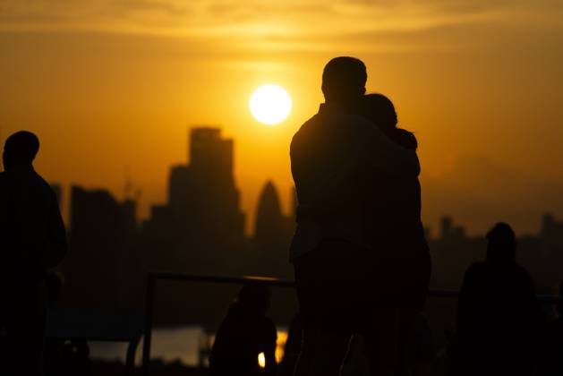 Two people hug as the watch the sunset over London on the Summer Solstice (21st June) seen from Greenwich Park, London. Greenwich London England Greenwich Park  Copyright: xBenjaminxGilbertx