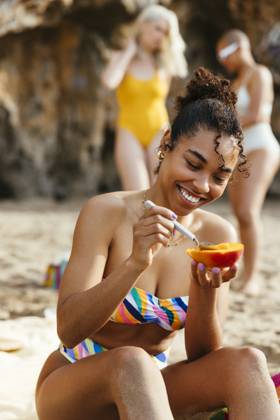 Young woman in bikini enjoying mango at beach model released, Symbolfoto, EBSF03360