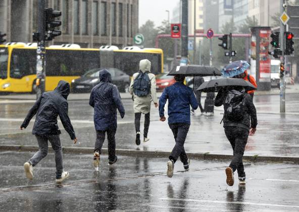 Rainy weather Berlin, 23 06 2023 People in rain gear run across a pedestrian walkway during heavy rainfall Strong thunderstorms have moved over parts of Germany Berlin Berlin Germany