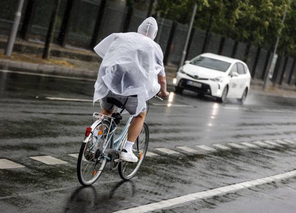 Rainy weather Berlin, 23 06 2023 A cyclist protects himself from heavy rainfall with a rain cape Strong thunderstorms have passed over parts of Germany Berlin Berlin Germany