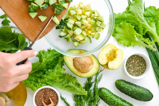 Woman cooking salad of fresh green vegetables and herbs. Raw food concept. Vegan menu. Cooking healthy diet or vegetarian food. Female hands cut cucumber on cutting board surrounded by green vegetables. Step by step recipe. Woman cooking salad of fresh green vegetables and herbs. Cooking healthy diet or vegetarian food. Female hands cut cucumber on cutting board surrounded by green vegetables. Step by step recipe. Healthy eating. Ingredients for salad. Pattern flat lay with healthy vegetarian meal ingredients. Raw food concept. A variety of organic fruits and vegetables with avocado. Vegan menu. Fresh spinach and green onion leaves. Copyright: xZoonar.com AnastasiiaxYanishevskax 18179516