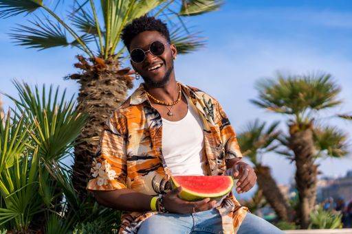 A shallow focus of a young handsome black man eating fresh watermelon at the beach *** einer seicht Fokus des einer Jung gutaussehenden Schwarz Mann essender Frisch Wassermelone im der Strand 19751170 ,model released, Symbolfoto RECORD DATE NOT STATED