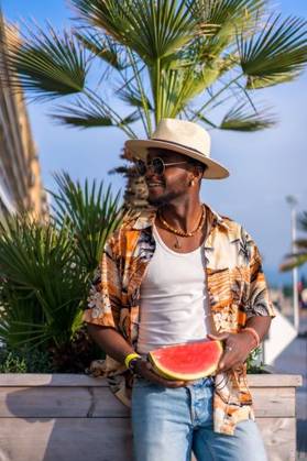 A shallow focus of a young handsome black man eating fresh watermelon at the beach *** einer seicht Fokus des einer Jung gutaussehenden Schwarz Mann essender Frisch Wassermelone im der Strand 19751178 ,model released, Symbolfoto RECORD DATE NOT STATED