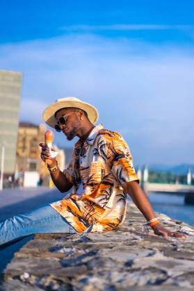 A shallow focus of a young handsome black man eating an ice cream cone at the beach *** einer seicht Fokus des einer Jung gutaussehenden Schwarz Mann essender An&Verkauf Eis Creme Kegel im der Strand 19751182 ,model released, Symbolfoto RECORD DATE NOT STATED