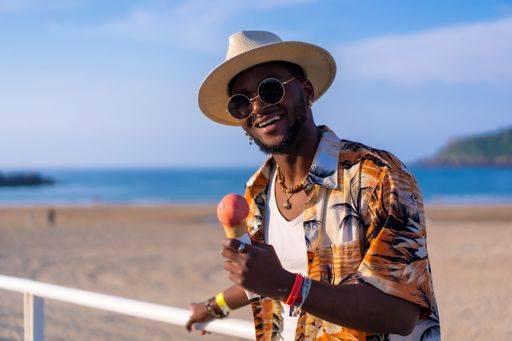 A shallow focus of a young handsome black man eating an ice cream cone at the beach *** einer seicht Fokus des einer Jung gutaussehenden Schwarz Mann essender An&Verkauf Eis Creme Kegel im der Strand 19751184 ,model released, Symbolfoto RECORD DATE NOT STATED
