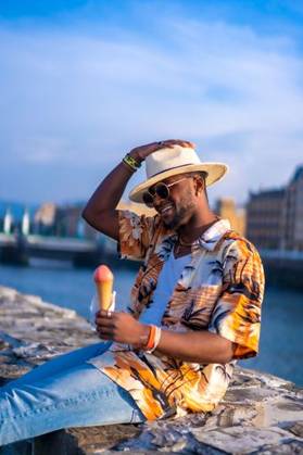 A shallow focus of a young handsome black man eating an ice cream cone at the beach *** einer seicht Fokus des einer Jung gutaussehenden Schwarz Mann essender An&Verkauf Eis Creme Kegel im der Strand 19751188 ,model released, Symbolfoto RECORD DATE NOT STATED