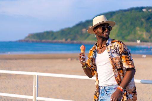 A shallow focus of a young handsome black man eating an ice cream cone at the beach *** einer seicht Fokus des einer Jung gutaussehenden Schwarz Mann essender An&Verkauf Eis Creme Kegel im der Strand 19751194 ,model released, Symbolfoto RECORD DATE NOT STATED