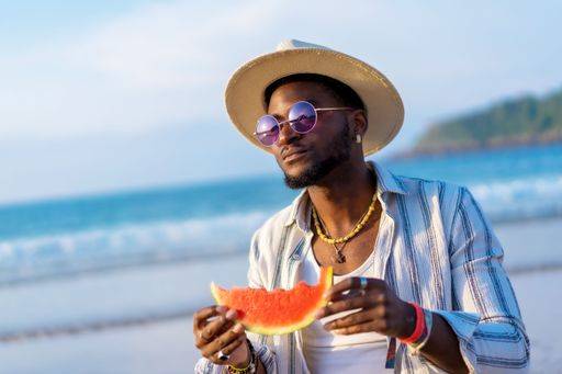A shallow focus of a young handsome black man eating fresh watermelon at the beach *** einer seicht Fokus des einer Jung gutaussehenden Schwarz Mann essender Frisch Wassermelone im der Strand 19751272 ,model released, Symbolfoto RECORD DATE NOT STATED