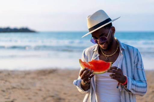 A shallow focus of a young handsome black man eating fresh watermelon at the beach *** einer seicht Fokus des einer Jung gutaussehenden Schwarz Mann essender Frisch Wassermelone im der Strand 19751276 ,model released, Symbolfoto RECORD DATE NOT STATED