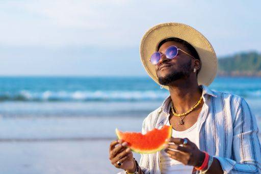 A shallow focus of a young handsome black man eating fresh watermelon at the beach *** einer seicht Fokus des einer Jung gutaussehenden Schwarz Mann essender Frisch Wassermelone im der Strand 19751278 ,model released, Symbolfoto RECORD DATE NOT STATED