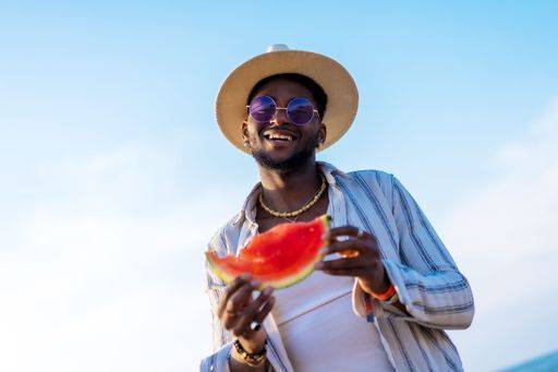 A shallow focus of a young handsome black man eating fresh watermelon at the beach *** einer seicht Fokus des einer Jung gutaussehenden Schwarz Mann essender Frisch Wassermelone im der Strand 19751280 ,model released, Symbolfoto RECORD DATE NOT STATED