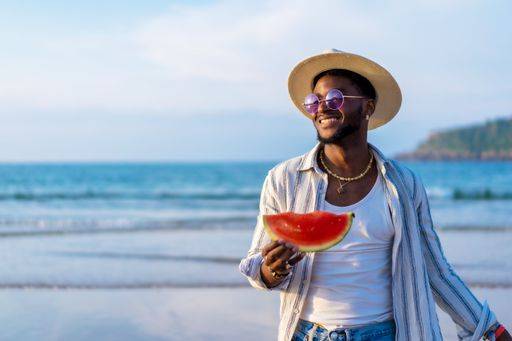 A shallow focus of a young handsome black man eating fresh watermelon at the beach *** einer seicht Fokus des einer Jung gutaussehenden Schwarz Mann essender Frisch Wassermelone im der Strand 19751290 ,model released, Symbolfoto RECORD DATE NOT STATED