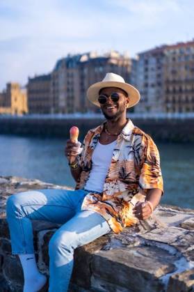 A shallow focus of a young handsome black man eating an ice cream cone at the beach *** einer seicht Fokus des einer Jung gutaussehenden Schwarz Mann essender An&Verkauf Eis Creme Kegel im der Strand 19751291 ,model released, Symbolfoto RECORD DATE NOT STATED