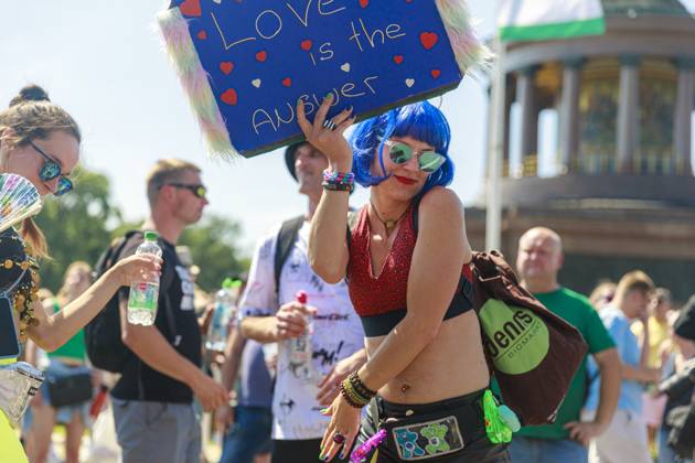 Rave the Planet 2023 Germany, Berlin on 08 July 2023 about 200 000 ravers and techno fans parade through the Tiergarten on the Starsse des 17 Juni on a hot summer day A young woman holds up a homemade sign that reads Love is the Answer