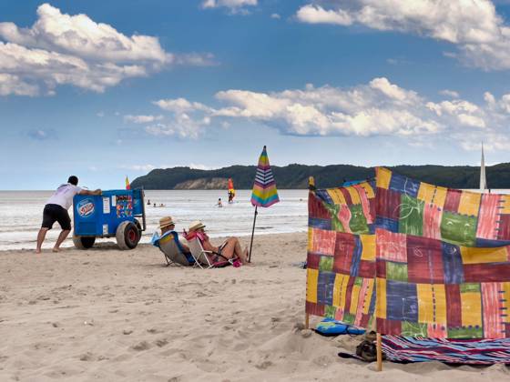 13 07 2023 View of the beach of Binz on the island of Rügen in Mecklenburg Vorpommern A man pushes an ice cream cart in front of him A couple sits in their beach chairs Binz is the largest seaside resort on the island of Rügen The municipality belongs