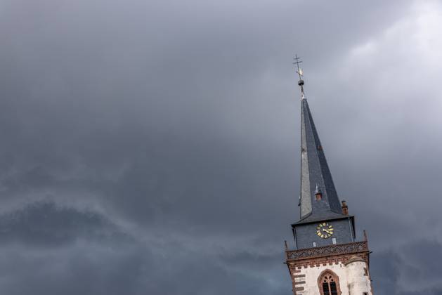 Dark clouds over the church tower Dark clouds of a thunderstorm are seen in the afternoon in the sky above the tower of the Catholic Church St Ursula , Oberursel Hesse Germany