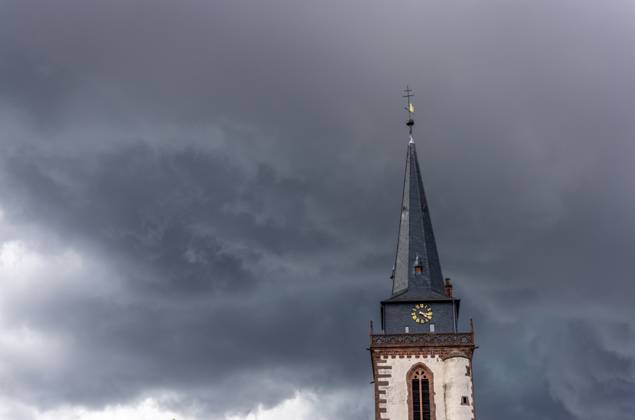 Dark clouds over the church tower Dark clouds of a thunderstorm are seen in the afternoon in the sky above the tower of the Catholic Church St Ursula , Oberursel Hesse Germany