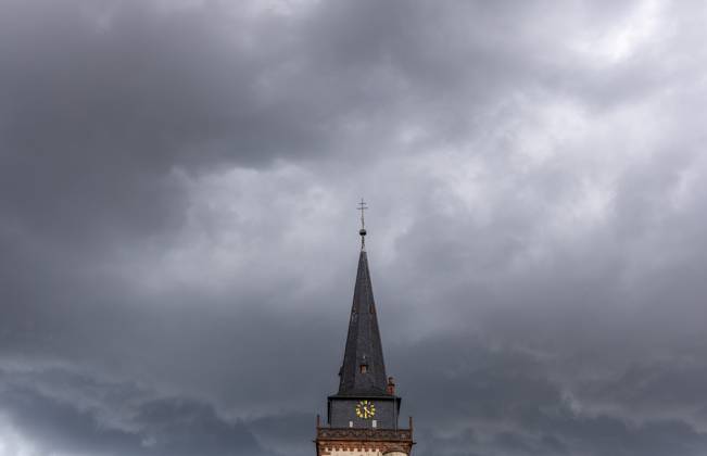 Dark clouds over the church tower Dark clouds of a thunderstorm are seen in the afternoon in the sky above the tower of the Catholic Church St Ursula , Oberursel Hesse Germany