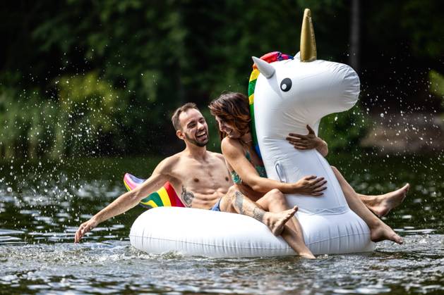 CREATIVE - Paar am See in Berlin Berlin, Deutschland - 25. Juli 2023: (CREATIVE) Ein Mann und eine Frau (Models) genießen auf einem aufgeblasenen Einhorn einen Sommertag an der Krummen Lanke, einem See in Berlin. Berlin