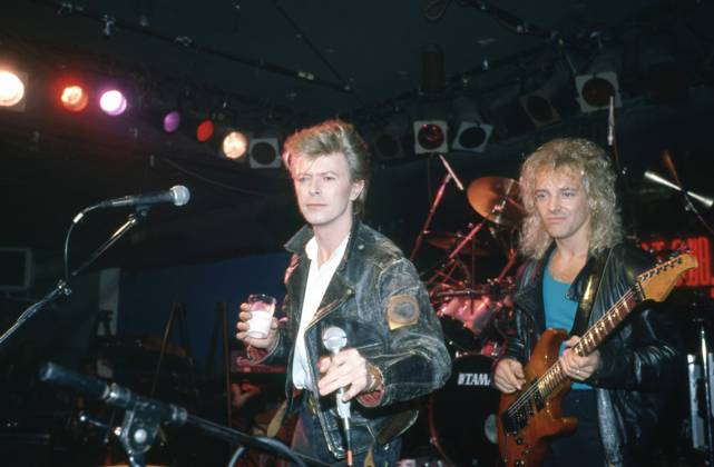 David Bowie performing on stage with drink in hand, wearing a black leather jacket, with Peter Frampton on guitar, New york, 1980s. Photo: Oscar Abolafia Everett Collection (davidbowie010)OSAB001 J4861 PUBLICATIONXNOTxINxCANxCHNxFRAxITAxJPNxNORxPOLxRUSxESPxUKxUSA Copyright: xx OSAB001 J4861 OSAB001_J4861_H