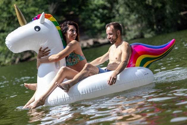 CREATIVE - Paar am See in Berlin Berlin, Deutschland - 25. Juli 2023: (CREATIVE) Ein Mann und eine Frau (Models) genießen auf einem aufgeblasenen Einhorn einen Sommertag an der Krummen Lanke, einem See in Berlin. Berlin