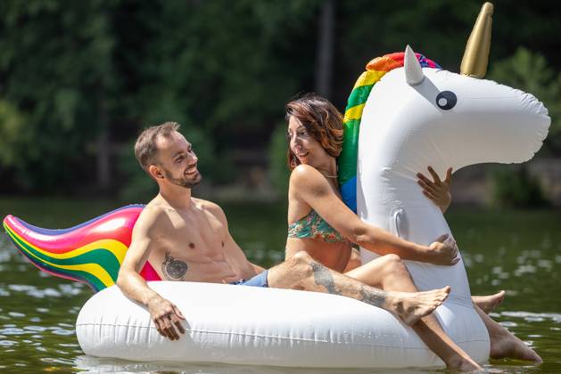 CREATIVE - Paar am See in Berlin Berlin, Deutschland - 25. Juli 2023: (CREATIVE) Ein Mann und eine Frau (Models) genießen auf einem aufgeblasenen Einhorn einen Sommertag an der Krummen Lanke, einem See in Berlin. Berlin