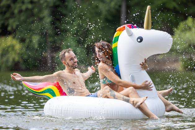 CREATIVE - Paar am See in Berlin Berlin, Deutschland - 25. Juli 2023: (CREATIVE) Ein Mann und eine Frau (Models) genießen auf einem aufgeblasenen Einhorn einen Sommertag an der Krummen Lanke, einem See in Berlin. Berlin